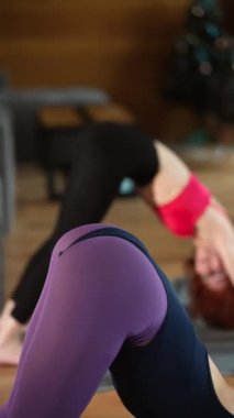 İki güzel kız evde yoga egzersizleri yapıyor. Vücutlarını esneterek alıştırma yapıyorlar. Gençler, iç mekanlar ve sağlıklı yaşam tarzı konsepti.
