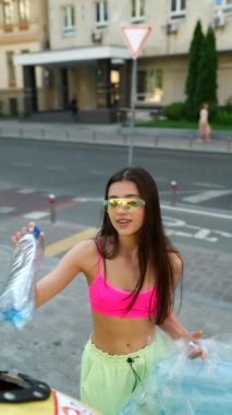 Genç yetişkin bir kız özel bir konteynıra plastik bir şişe atar. Plastik geri dönüşüm, düzgün çöp ayıklama. Yüksek kalite 4k görüntü
