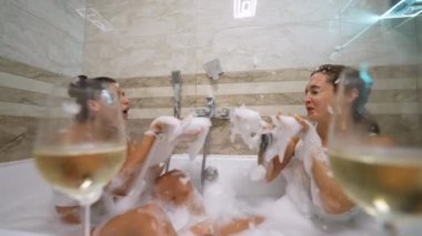 Beyaz tişörtlü iki güzel kız banyoda sabunla oynarken eğleniyor. Yüksek kalite 4k görüntü