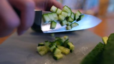 yeşil salatalıklar mutfakta bıçakla kesilir. Sağlıklı sebze salatası konsepti. Mutfaktaki yeşil salatalıklar yakın plan yaşam tarzını dilimlere ayırıyor. Yüksek kalite 4k görüntü