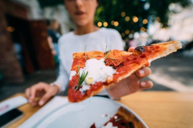 Kadın eli terasta bir dilim pizzayı tutuyor.. 