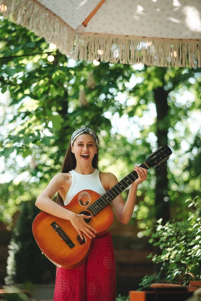 stock image Happy hippie girl is having a good time with playing on guitar in camper trailer. Holiday, vacation, trip concept.High quality photo