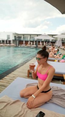 Bikinili genç seksi kız sahilde kokteyl içiyor. Yüksek kalite 4k görüntü