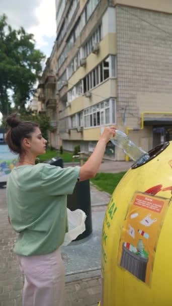 少女は特殊な容器にペットボトルを投げ込む プラスチックのリサイクル ゴミの適切な分類 高品質4K映像 — ストック動画