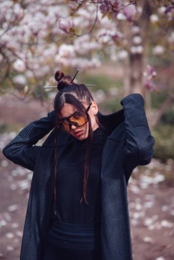 Kimono giyen, kiraz çiçekli sarı gözlüklü, sakura manzaralı güzel bir genç kadın. Yüksek kalite fotoğraf