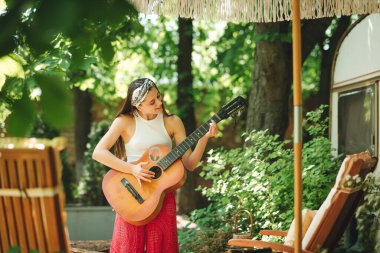 Mutlu hippi kız karavanda gitar çalarak iyi vakit geçiriyor. Tatil, tatil, gezi konsepti. Yüksek kalite fotoğraf.