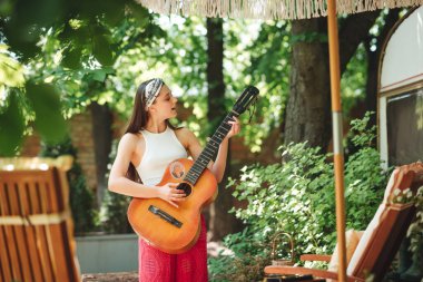 Mutlu hippi kız karavanda gitar çalarak iyi vakit geçiriyor. Tatil, tatil, gezi konsepti. Yüksek kalite fotoğraf.
