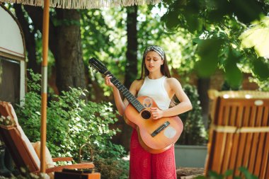 Mutlu hippi kız karavanda gitar çalarak iyi vakit geçiriyor. Tatil, tatil, gezi konsepti. Yüksek kalite fotoğraf.