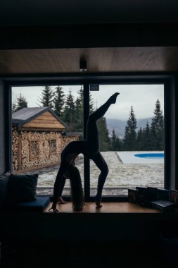 Güzel kız evde yoga egzersizleri yapıyor evde vücudunu esneterek yerde pratik yapıyor. Gençler, iç mekanlar ve sağlıklı yaşam tarzı konsepti.