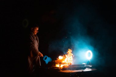 Adam barbeküyü ateşte pişirmek için hazırlıyor. Karanlık şutun dışında. Ateşin donma anı. Yüksek kalite fotoğraf