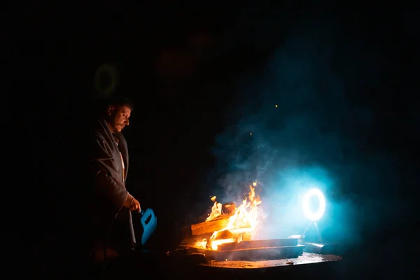 火で調理するためにバーベキューグリルを準備している男 暗いショットの外 火災の瞬間を凍結します 高品質の写真 — ストック写真