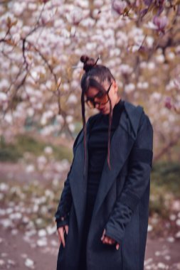 Siyah kimono giyen, kiraz çiçekli sarı gözlüklü, sakura manzaralı güzel, dramatik bir genç kadın. Yüksek kalite fotoğraf