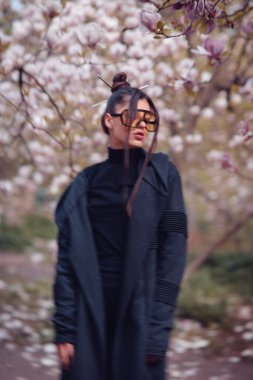 Siyah kimono giyen, kiraz çiçekli sarı gözlüklü, sakura manzaralı güzel, dramatik bir genç kadın. Yüksek kalite fotoğraf