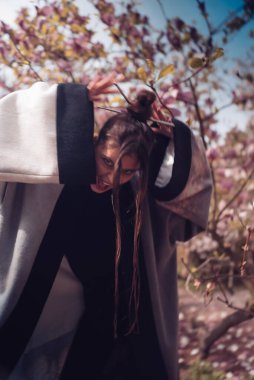 Kiraz çiçekli kimono giyen güzel, dramatik genç bir kadın, sakura manzaralı. Yüksek kalite fotoğraf