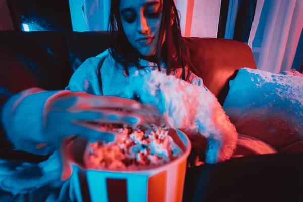 在家里用爆米花桶和她的狗一起在黑暗的房间里 坐在监视器或电视前看电影的漂亮小女孩的近照 疯狂的感情高质量的照片 — 图库照片