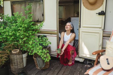 Mutlu hippi kız karavanda bir fincan çayla iyi vakit geçiriyor. Tatil, tatil, gezi konsepti. Yüksek kalite fotoğraf.