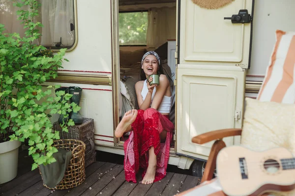 ハッピーヒッピーの女の子は キャンパートレーラーでお茶のカップと楽しい時間を過ごしています 旅行のコンセプト 高品質の写真 — ストック写真