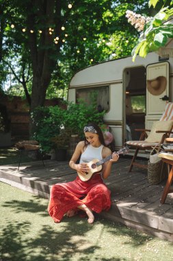 Mutlu hippi kız karavanda gitar çalarak iyi vakit geçiriyor. Tatil, tatil, gezi konsepti. Yüksek kalite fotoğraf.