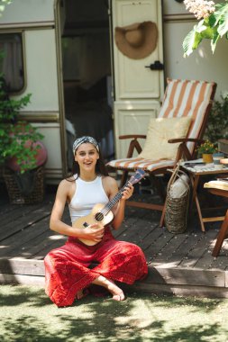Mutlu hippi kız karavanda gitar çalarak iyi vakit geçiriyor. Tatil, tatil, gezi konsepti. Yüksek kalite fotoğraf.