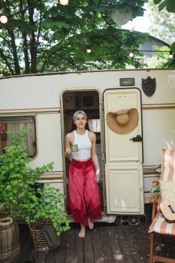 Mutlu hippi kız karavanda bir fincan çayla iyi vakit geçiriyor. Tatil, tatil, gezi konsepti. Yüksek kalite fotoğraf.