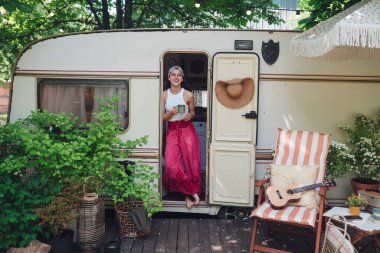 Mutlu hippi kız karavanda bir fincan çayla iyi vakit geçiriyor. Tatil, tatil, gezi konsepti. Yüksek kalite fotoğraf.