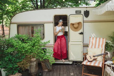 Mutlu hippi kız karavanda bir fincan çayla iyi vakit geçiriyor. Tatil, tatil, gezi konsepti. Yüksek kalite fotoğraf.