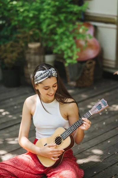 stock image Happy hippie girl are having a good time with playing on guitar in camper trailer. Holiday, vacation, trip concept.High quality photo