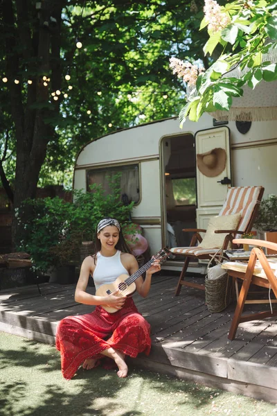 快乐的嬉皮士女孩在露营拖车上弹奏吉它很开心 旅行的概念 高质量的照片 — 图库照片