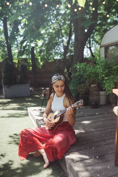 Mutlu hippi kız karavanda gitar çalarak iyi vakit geçiriyor. Tatil, tatil, gezi konsepti. Yüksek kalite fotoğraf.