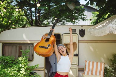Mutlu hippi kız karavanda gitar çalarak iyi vakit geçiriyor. Tatil, tatil, gezi konsepti. Yüksek kalite fotoğraf.