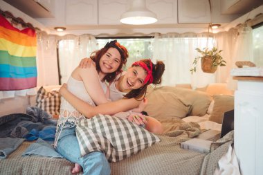 Sevimli lezbiyen bir çiftin portresi. İki kız, duvarında LGBT bayrağı olan bir karavanda şefkatle vakit geçiriyorlar. Aşk ve tutum. LGBT konsepti. Yüksek kalite fotoğraf