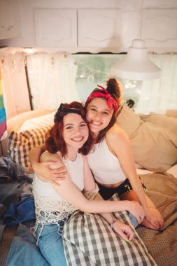 Sevimli lezbiyen bir çiftin portresi. İki kız, duvarında LGBT bayrağı olan bir karavanda şefkatle vakit geçiriyorlar. Aşk ve tutum. LGBT konsepti. Yüksek kalite fotoğraf