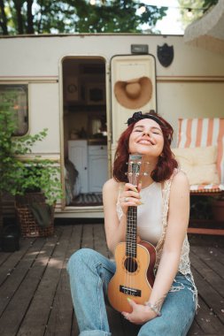 Mutlu hippi kız karavanda gitar çalarak iyi vakit geçiriyor. Tatil, tatil, gezi konsepti. Yüksek kalite fotoğraf.