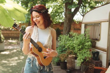 Mutlu hippi kız karavanda gitar çalarak iyi vakit geçiriyor. Tatil, tatil, gezi konsepti. Yüksek kalite fotoğraf.