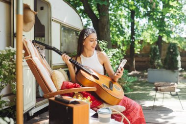 Mutlu hippi kız karavanda gitar çalarak iyi vakit geçiriyor. Tatil, tatil, gezi konsepti. Yüksek kalite fotoğraf.