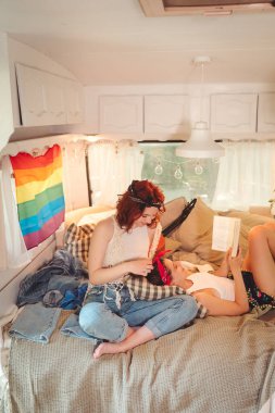 Sevimli lezbiyen bir çiftin portresi. İki kız, duvarında LGBT bayrağı olan bir karavanda şefkatle vakit geçiriyorlar. Aşk ve tutum. LGBT konsepti. Yüksek kalite fotoğraf