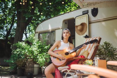 Mutlu hippi kız karavanda gitar çalarak iyi vakit geçiriyor. Tatil, tatil, gezi konsepti. Yüksek kalite fotoğraf.