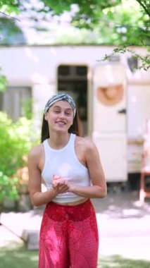 The beautiful hippie girl is talking in front of the trailer. High quality 4k footage
