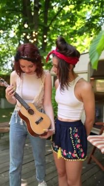 Two hippie girls with a guitar near the trailer. High quality 4k footage