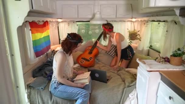 Two Beautiful Hippie Girls Relax Bed Trailer Chatting Laptop Book — Wideo stockowe