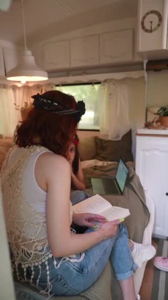 Two Beautiful Hippie Girls Sitting Bed Trailer Chatting Laptop Book — Video