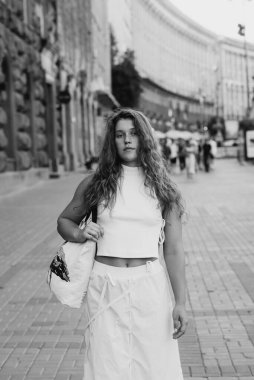 A black-and-white picture of a chic young girl with curly hair. High quality photo