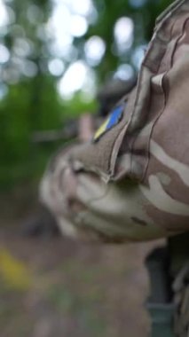 Asker, ormanda silahlı bir şekilde yürürken Ukrayna bayrağını üniformalarında taşıyor. Yüksek kalite 4k görüntü