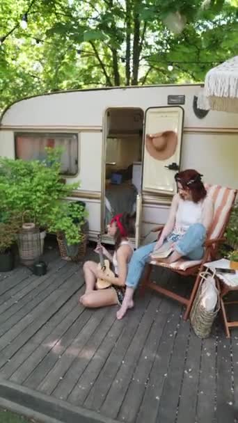 预告片背景 有两个嬉皮士女孩 一个沉浸在吉他手的旋律中 另一个沉迷于阅读 高质量的4K镜头 — 图库视频影像