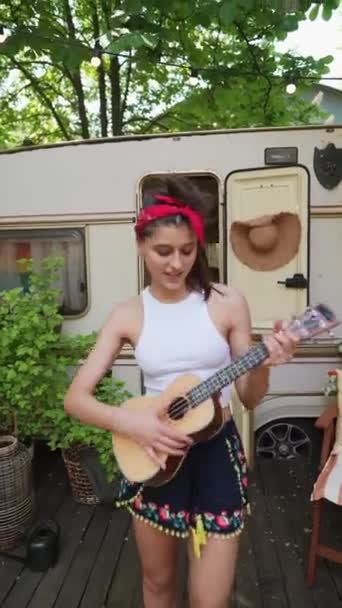一个穿着时髦的女孩 带着嬉皮士的气氛弹吉他 高质量的4K镜头 — 图库视频影像