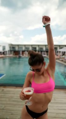 Plajda elinde kokteylle dans eden bikinili güzel seksi bir kız. Yüksek kalite 4k görüntü