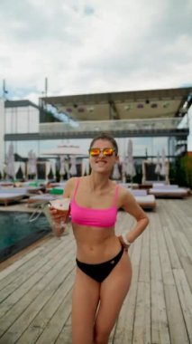 Plajda elinde kokteylle dans eden bikinili güzel seksi bir kız. Yüksek kalite 4k görüntü