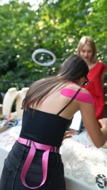 Bileklerinde pembe bantlarla neşeli ve modaya uygun bir kadın fuarda süs eşyası arıyor. Yüksek kaliteli FullHD görüntüler