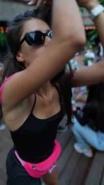 Coşkuyla, canlı ve şık genç bir kadın parktaki festivalde dans ediyor. Yüksek kaliteli FullHD görüntüler