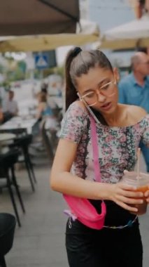 Yoğun saatlerde, enerjik genç bir kız telefonda konuşurken caddede aceleyle yürür. Yüksek kalite 4k görüntü